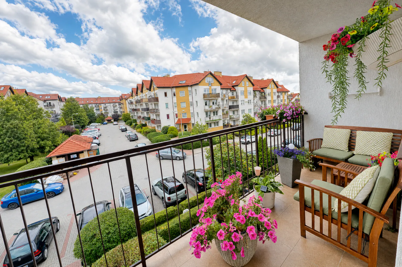 Duży, urządzony balkon z widokiem na zielone osiedle